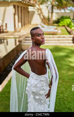 Persona fluida di genere ambigua in elegante abito bianco in villa. Scena del matrimonio LGBTQ. Moderno stile nuziale. Giardino tropicale. Amore inclusivo Foto Stock