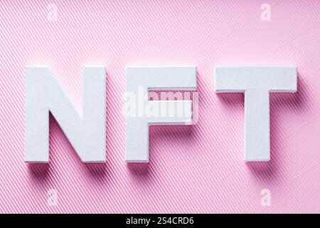 Lettere bianche NFT su sfondo a strisce diagonali rosa, concetto di arte crittografica, vista dall'alto Foto Stock