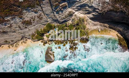Vista a volo d'uccello delle onde dell'oceano che si infrangono contro le scogliere verticali e una piccola spiaggia Foto Stock