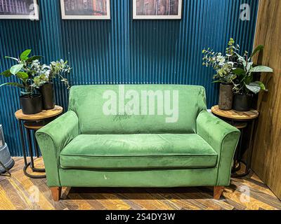 Un divano verde in un'area d'attesa in uno spogliatoio in un negozio di abbigliamento di lusso. Foto Stock