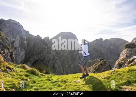 Fotografo che scatta foto di una valle tra le montagne di aiako harria, noto anche come penas de aia, a oiartzun, Paesi baschi Foto Stock