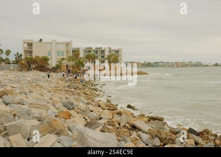 St. Pete Beach, Florida, Pass-a-Grille Beach Vista a sud su grandi rocce, molte persone verso Shell Key Island. Nel tardo pomeriggio, nuvoloso. Grande Foto Stock