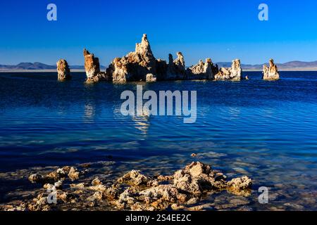 Un'isola rocciosa si trova nel mezzo di un grande specchio d'acqua. L'acqua è calma e blu e l'isola è circondata da rocce. La scena è pacifica Foto Stock