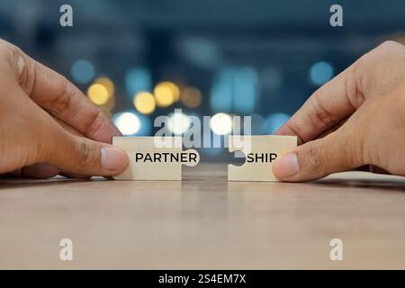 Due mani con due pezzi di puzzle per formare la parola "PARTNERSHIP". Concetto di collaborazione e lavoro di squadra. Foto Stock