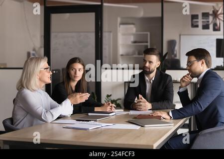Una donna d'affari di mezza età fa un discorso durante una riunione formale con gli azionisti Foto Stock