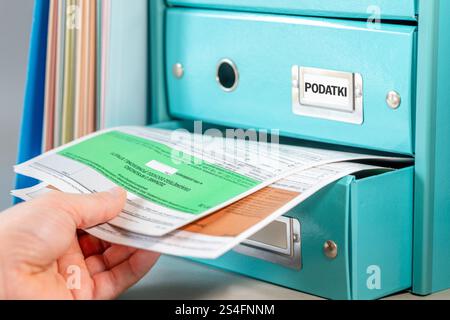 Tasse Polonia. Liquidazione dell'imposta sul reddito delle persone fisiche. Concetto finanziario. Persona che entra in un cassetto per i moduli di liquidazione dell’imposta annuale sul reddito delle persone fisiche in P Foto Stock