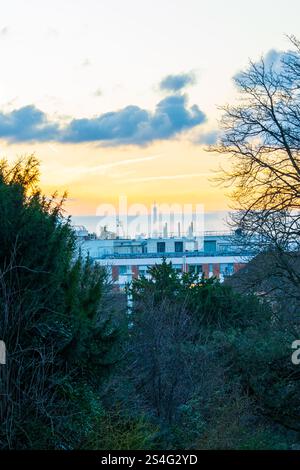 Vista di un tramonto su una città costiera con un faro distante in vista Foto Stock