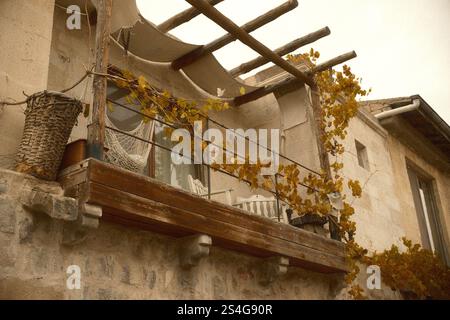 Un balcone rustico con pergolato in legno, amaca e foglie dorate sulle vigne in autunno Foto Stock