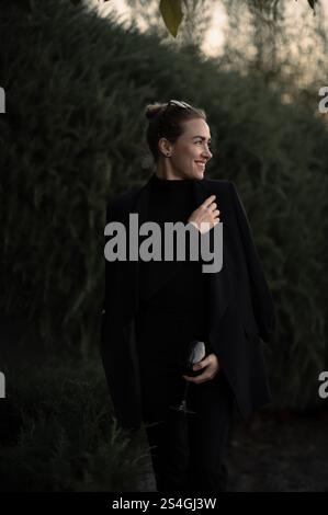 Ragazza con un bicchiere di vite a una festa sul retro in abito nero Foto Stock