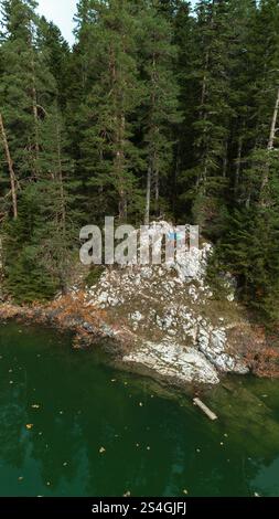 Una giovane coppia sta viaggiando con due cani, in piedi sbattendo le mani sul bordo di una scogliera. Veduta aerea del Lago Nero - Crno Jezero. Durmi Foto Stock