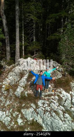 Una giovane coppia sta viaggiando con due cani, in piedi sbattendo le mani sul bordo di una scogliera. Veduta aerea del Lago Nero - Crno Jezero. Durmi Foto Stock