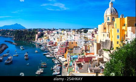 Viaggi in Italia e luoghi di interesse. L'isola più pittoresca e colorata - la bellissima Procida nel golfo di Napoli. Vista panoramica del porto di Corricella con chiesa gialla Foto Stock