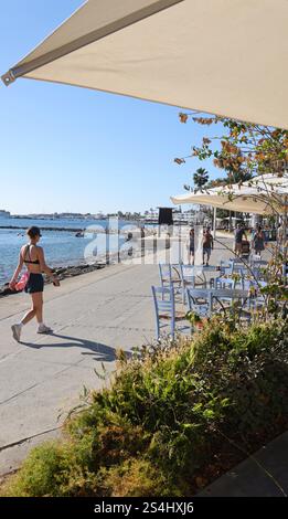 Una giovane donna cammina lungo il lungomare verso il porto di Pafo, Cipro. Ottobre 2024 Foto Stock