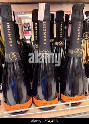 Bobruisk, Bielorussia - 2 gennaio 2025: Una fila di eleganti bottiglie di champagne con dettagli in vetro scuro e oro attende gli acquirenti su uno scaffale in un vivace negozio. Foto Stock