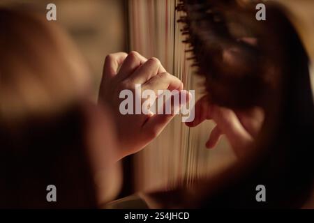 Primo piano di una musicista professionista che suona l'arpa succhiando delicatamente le corde mentre esegue un'incantevole melodia sul palco, spazio copia Foto Stock