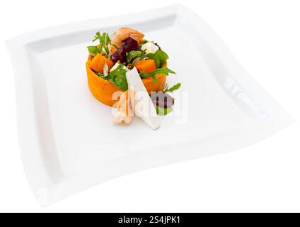 Un'insalata vivace con gamberi, verdure fresche e verdure a dadini è elegantemente disposta su un piatto bianco, che presenta un piatto colorato e sano pe Foto Stock