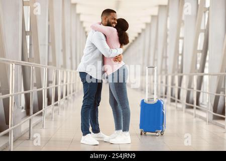 Uomo nero felice che abbraccia sua moglie in aeroporto Foto Stock