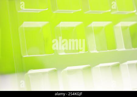 Uno stampo per termoformatura quadrato trasparente industriale realizzato in plastica come soluzione di imballaggio per prodotti industriali. Vassoio in alluminio su sfondo verde. Foto Stock
