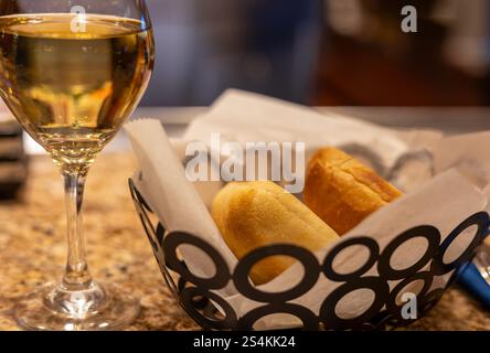 Allevato nel cestino e un bicchiere di vino bianco sul tavolo. Primo piano, messa a fuoco selettiva Foto Stock