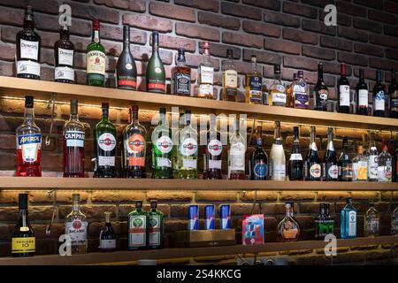 Si tratta di una collezione vibrante e colorata di bottiglie di liquori che sono ordinatamente disposte su un elegante scaffale da bar Martini e altri alcolici in mostra di nuovo Foto Stock