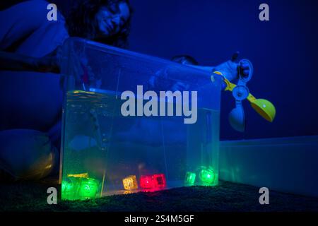 Bambino e terapista in camera stimolante sensoriale, Black snoezelen. Bambino autistico che gioca con il terapista durante la sessione di terapia occupazionale. Foto Stock