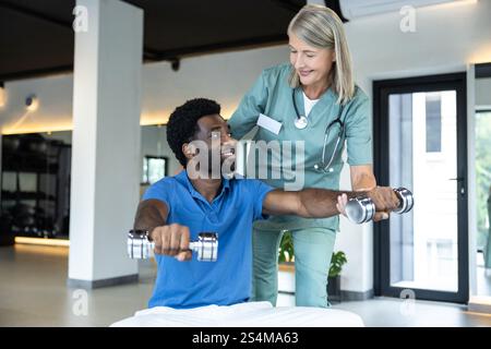 Giovane afroamericano che lavora sulle sue braccia, medico donna che lo guida Foto Stock