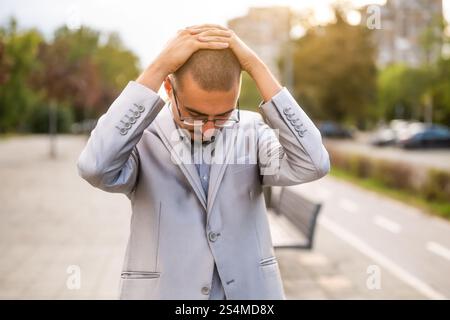 Ritratto di un giovane uomo d'affari ansioso e scontento che si trova in strada. Uomo d'affari esausto e deluso dopo il lavoro. Foto Stock