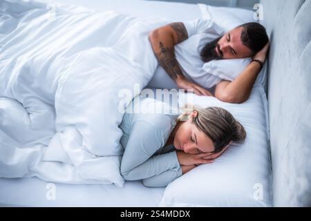 Una giovane coppia sposata sta dormendo nel loro letto. Foto Stock