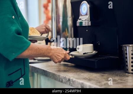 Una donna prepara caffè fresco e fragrante utilizzando una moderna macchina per il caffè. Con spazio per copiare. Foto di alta qualità Foto Stock