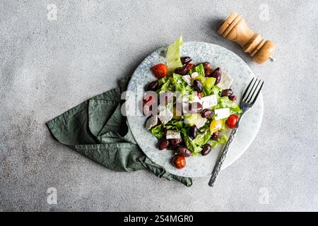 Una vivace insalata greca con pomodori, lattuga, olive fermentate rosse e formaggio feta, condito con olio Foto Stock