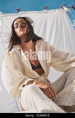 Un ambiente estivo sereno con una donna sul tetto che indossa un abito arioso. Il morbido tessuto scorre dolcemente al sole, catturando un momento di relax Foto Stock