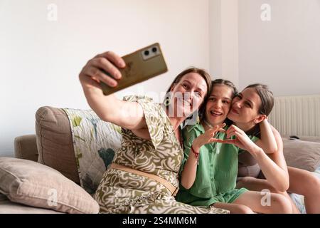 Un caldo momento in famiglia per catturare una madre e due figlie, tra cui una con tracheostomia, scattare un selfie mentre si divertono insieme su una Foto Stock