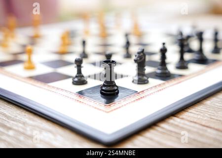 Primo piano di una scacchiera su un tavolo di legno all'aperto pezzi in bianco e nero disposti per un gioco in corso, catturando il gioco strategico e rilassato Foto Stock