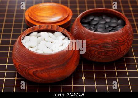 Bianco e nero convessa doppia yunzi pietre in ciotola di legno su tavola Foto Stock