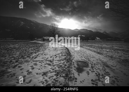 Bianco e nero paesaggio di strada innevata nelle Alpi al tramonto Foto Stock