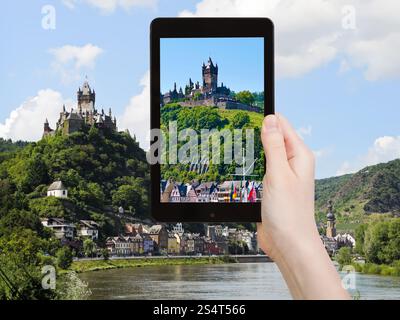Concetto di viaggio - il turista scatta una foto della città di Cochem sulla Mosella e del castello imperiale di Cochem sulla città in Germania su smartphone, Foto Stock