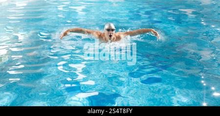 Giovane atleta bello nuotare in sondaggio in stile a farfalla Foto Stock