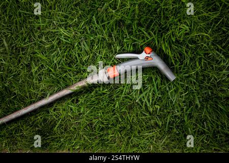 Primo piano del giardino tubo flessibile giacente sulla fresca erba verde Foto Stock