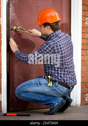 Professional carpenter modifica serratura in metallo pesante porta Foto Stock