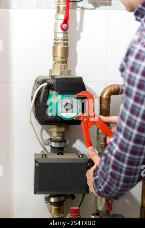 Closeup colpo di plumber riparazione impianto di riscaldamento con una pinza rossa Foto Stock