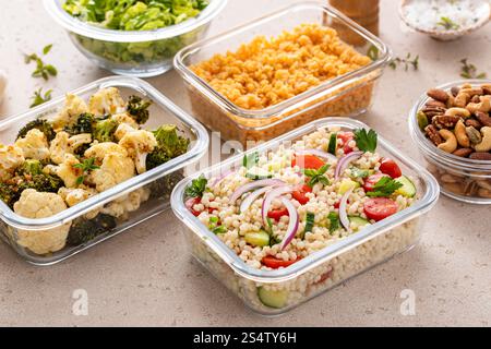 Preparazione dei pasti vegani in contenitori con lenticchie, verdure arrostite, noci e insalata di couscous perle Foto Stock