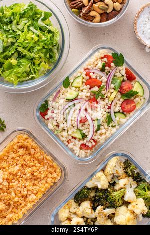 Preparazione dei pasti vegani in contenitori con lenticchie, verdure arrostite, noci e insalata di couscous perle Foto Stock