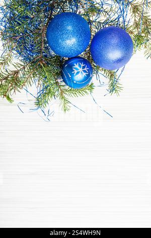 Auguri di Natale - Scheda di confine da tre blu Xmas baubles e ramo di albero su carta bianca sullo sfondo Foto Stock