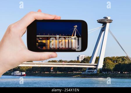 Concetto di viaggio - tourist snapshot di SNP Bridge (ponte di UFO, Novy più, ponte nuovo) oltre il fiume Danubio a Bratislava sullo smartphone Foto Stock