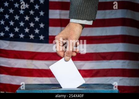 Mano che colloca il voto in una casella elettorale con la bandiera degli Stati Uniti nel concetto di elezioni in background Foto Stock