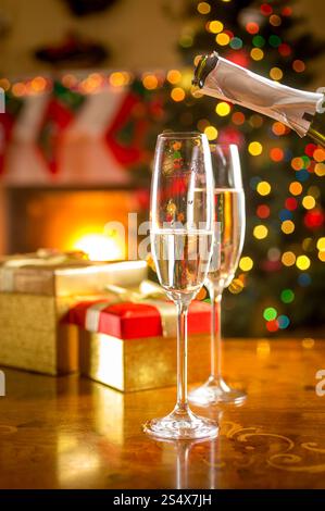 Primo piano di due bicchieri di essere riempita di champagne alla vigilia di Natale Foto Stock