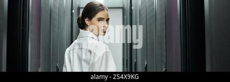 Specialista IT in una camicia bianca che gestisce abilmente i server in un moderno data center, banner Foto Stock
