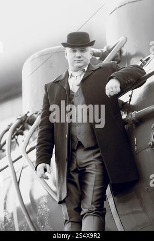 Bianco e nero ritratto di uomo in cappello bowler permanente sulla vecchia locomotiva Foto Stock