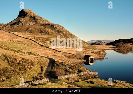 Una casa di barche si trova sul bordo dei laghi di Cregennan, o Llynnau Cregennan, vicino a Arthog, Dolgellau, Galles del Nord con la cresta di Pared y Cefn hîr sopra Foto Stock