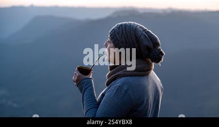 Donna che si diverte con yerba mate nelle tranquille montagne invernali di Serra Gaúcha, Brasile Foto Stock
